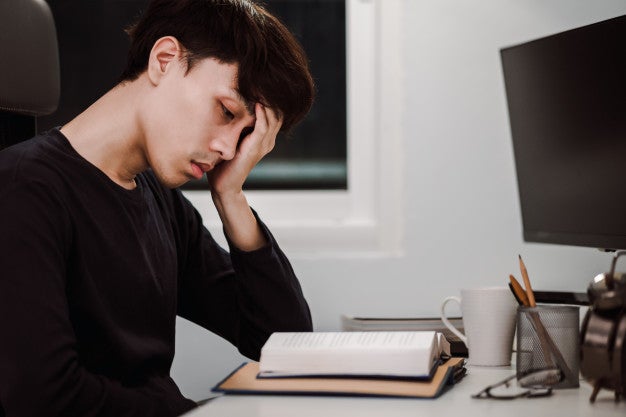 exhausted young asian man heavy reading book work desk late night knowledge learning concept 34168 1906