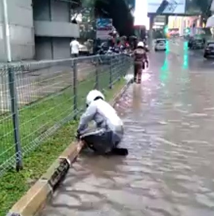 Watch: Dedicated KL Police Unclogs Drain Using His Own Hand During Flash Flood - WORLD OF BUZZ 1