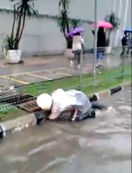 Watch: Dedicated KL Police Unclogs Drain Using His Own Hand During Flash Flood - WORLD OF BUZZ 2