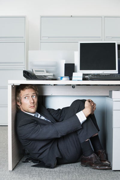 business man hiding under desk