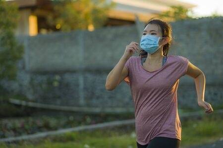 145915301 asian woman in anti pollution face mask running workout young dedicated girl jogging at beautiful ci