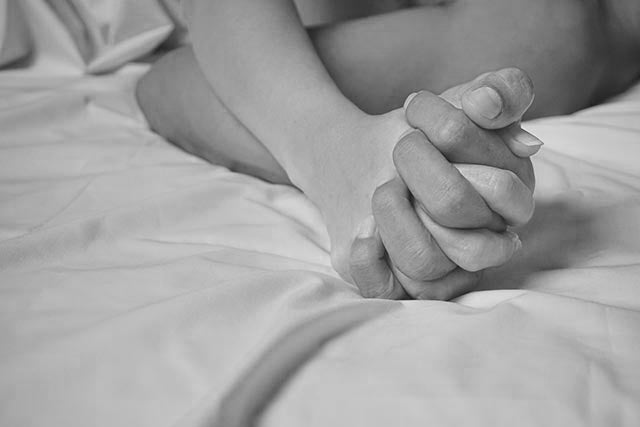 man and woman holding hands on a beds