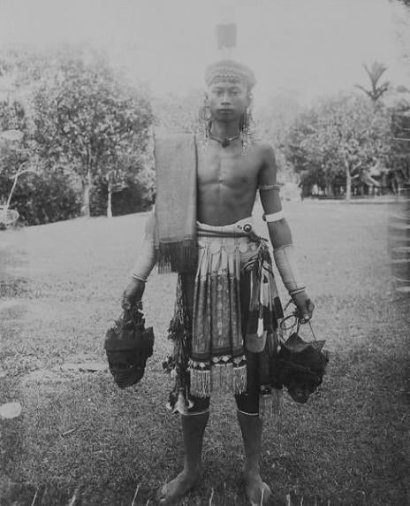 Dayak man in possession of two heads on strings
