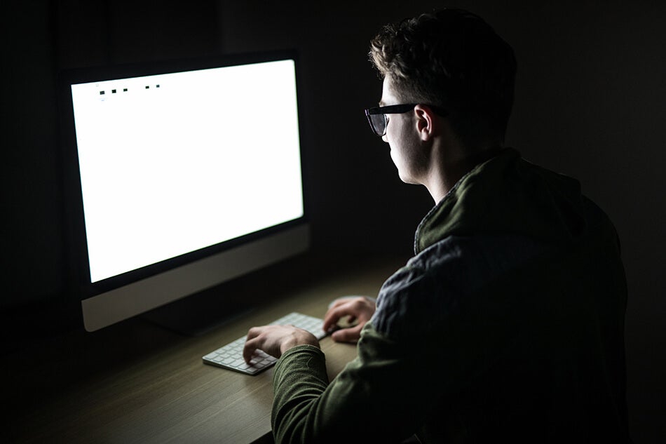 man using computer dark room