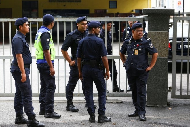 malaysian police officers gather in front of the gate of the morgue at kuala lumpur general hospital
