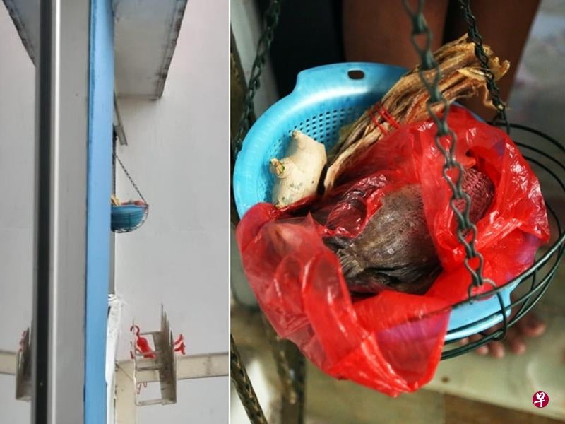 Hanging basket from window containing salted fish in red plastic bag