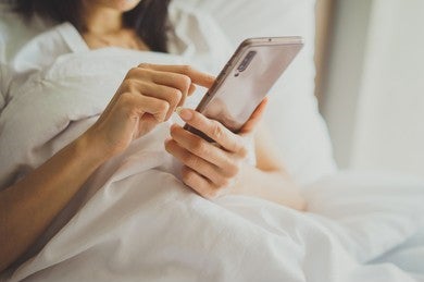 Woman Using Phone In Bed