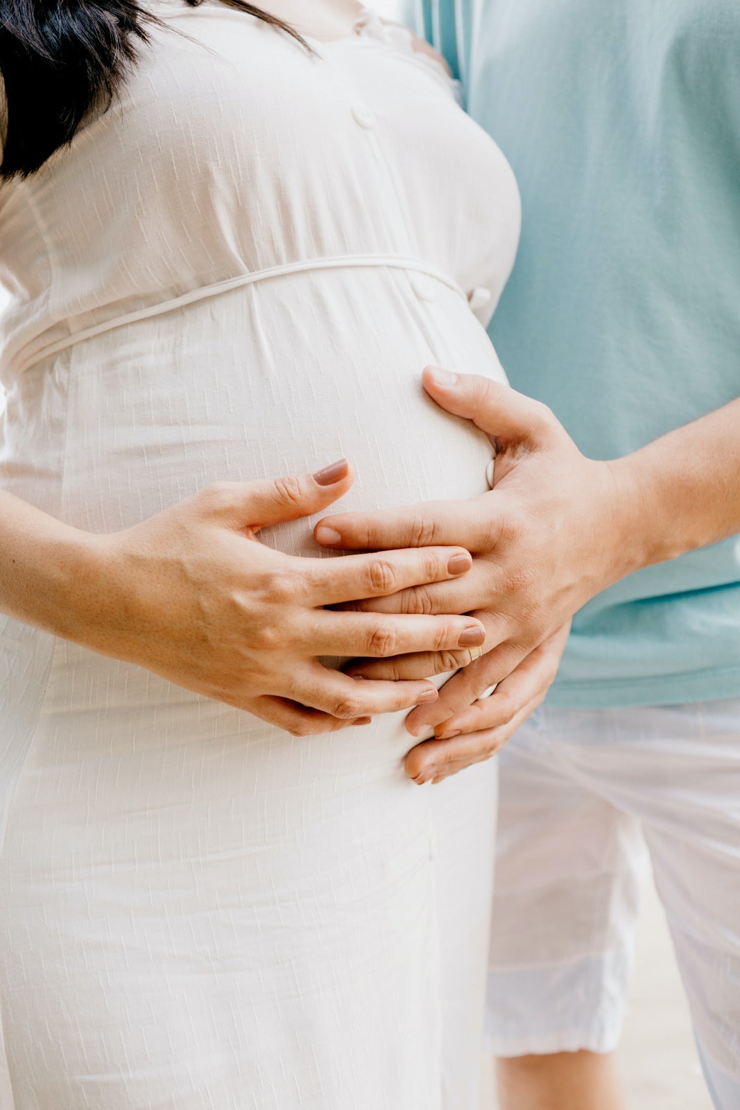 Pregnant woman hand on tummy with husband