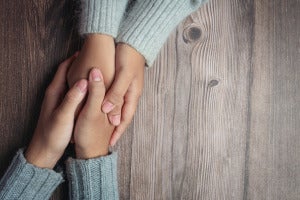 two people holding hands together with love warmth wooden table