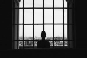 black white shot lonely female standing front windows looking buildings