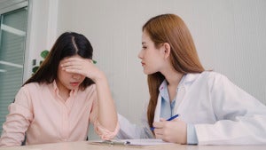 doctor talking unhappy teenage patient exam room
