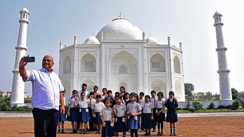 indian businessman anand prakash chouksey left poses along with visiting schoolchildren in front of a replica of the taj mahal at burhanpur in indias madhya pradesh state on thursday. afp