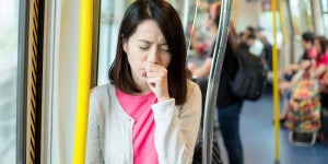 Girl coughing on train while covering her mouth with hand FE CA 1000x500 1
