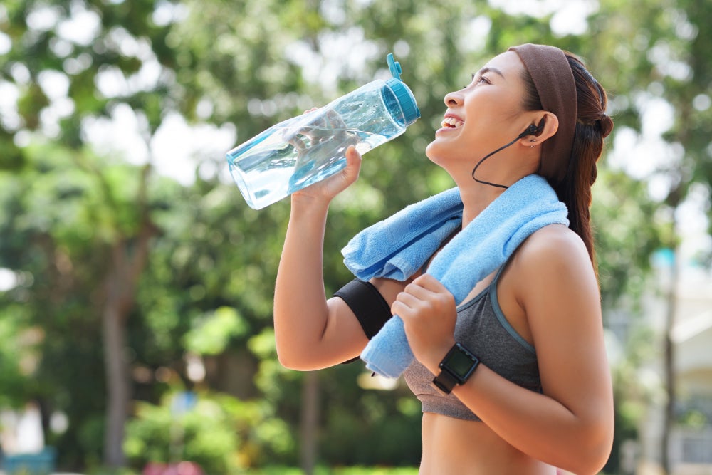 happy sportswoman drinking water park