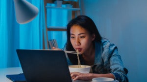asia freelance smart business women eating instant noodles while working laptop living room home night happy young asian girl sitting desk work overtime enjoy relax time