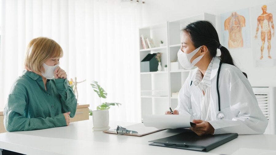 young asian lady doctor wearing protective mask using clipboard discussing results symptoms with girl patient hospital office 7861 2841