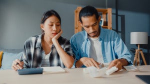 stressed asian couple man woman use calculator calculate family budget