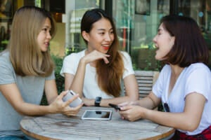 cheerful asian young women sitting cafe drinking coffee with friends talking together
