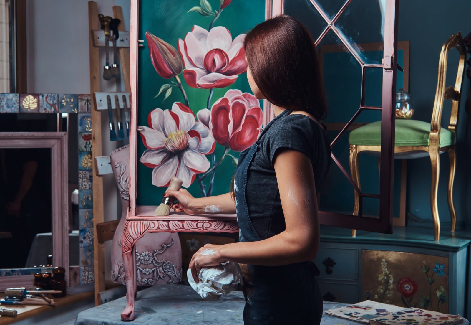 woman artist painting vintage renovated bookshelf workshop