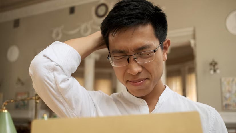 upset asian male student opening envelope with exam results library sadly holding head 574295 2085