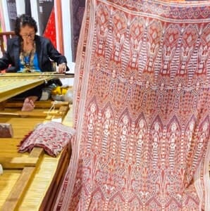 Bangie anak Embol at her backstrap loom with her participating piece in the foreground