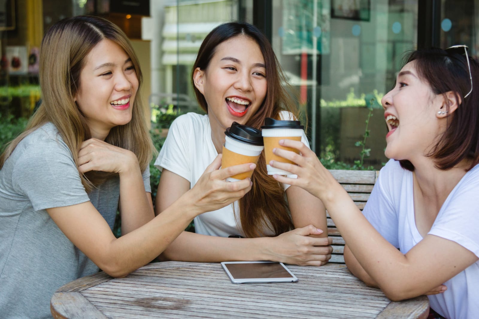 cheerful asian young women sitting cafe drinking coffee with friends talking together