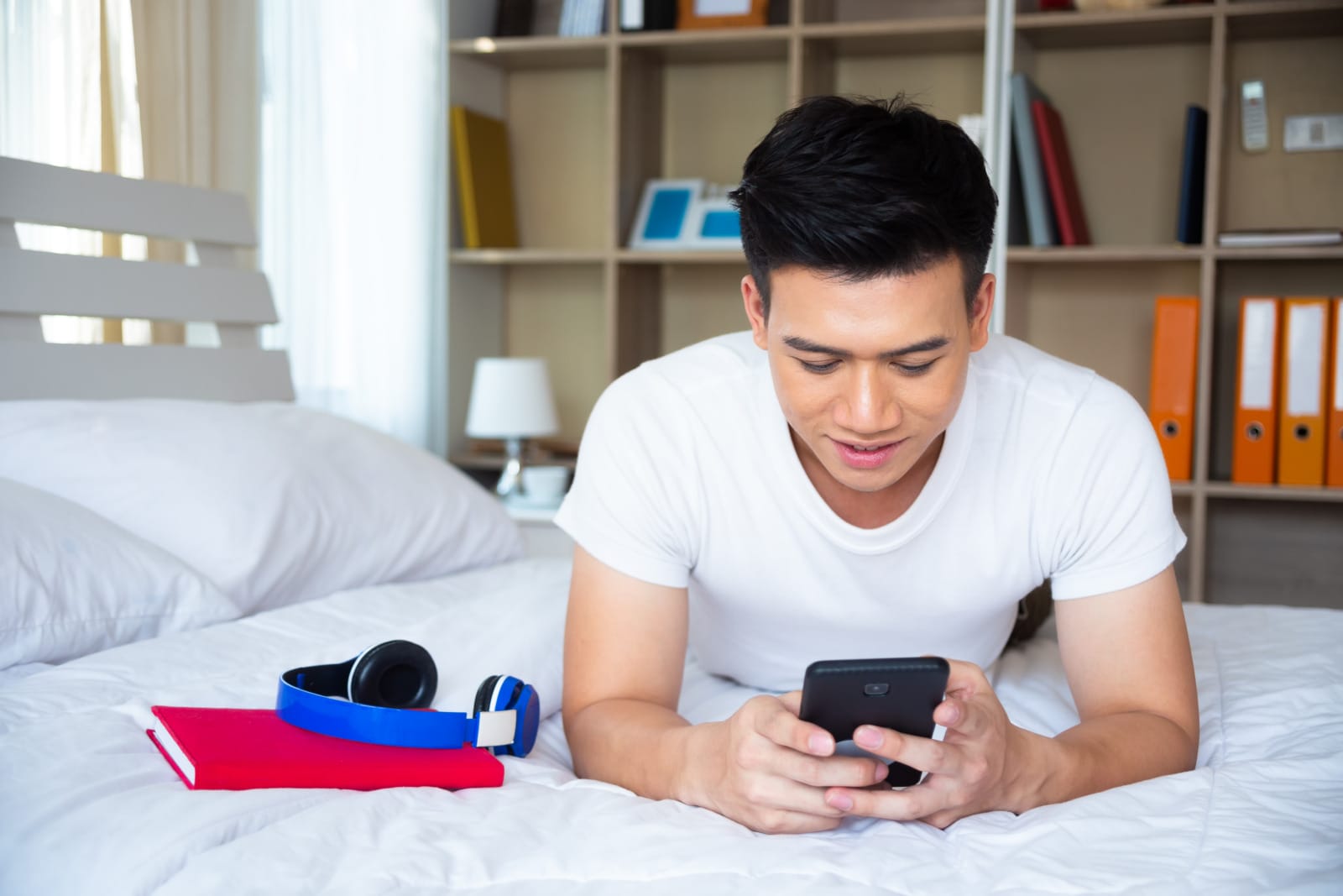 handsome young man lying bed use smartphone