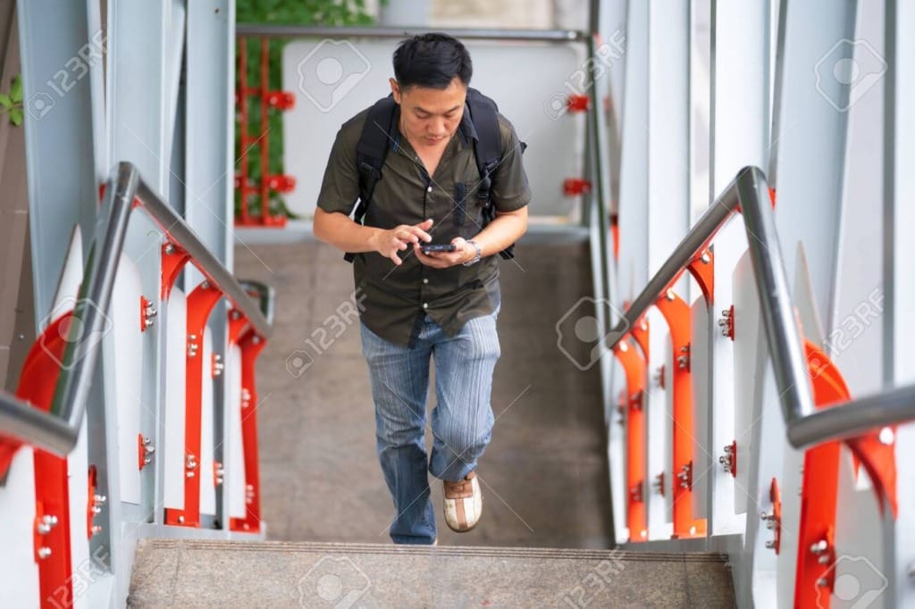 131525295 man walking up stairs and using smartphone in city
