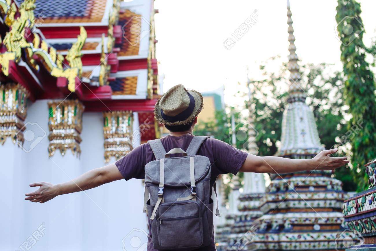 91281775 young man traveling backpacker spreading arms in wat pho in bangkok thailand