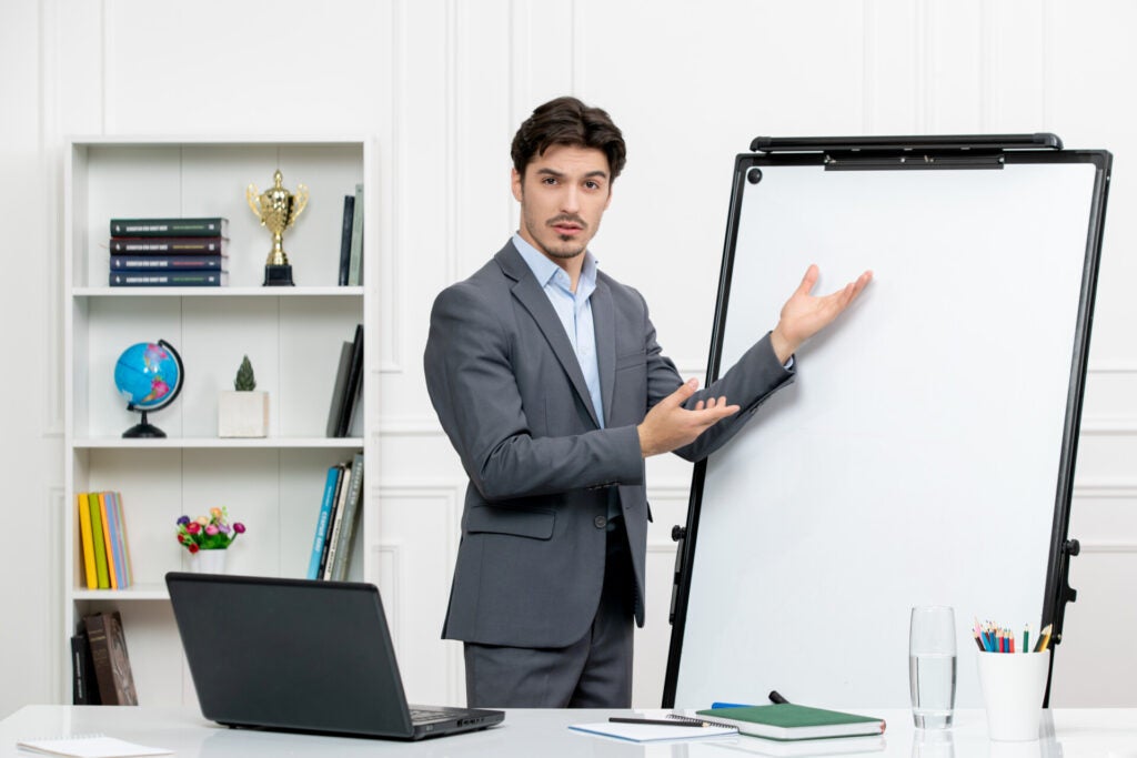 teacher smart instructor grey suit classroom with computer whiteboard explaining math