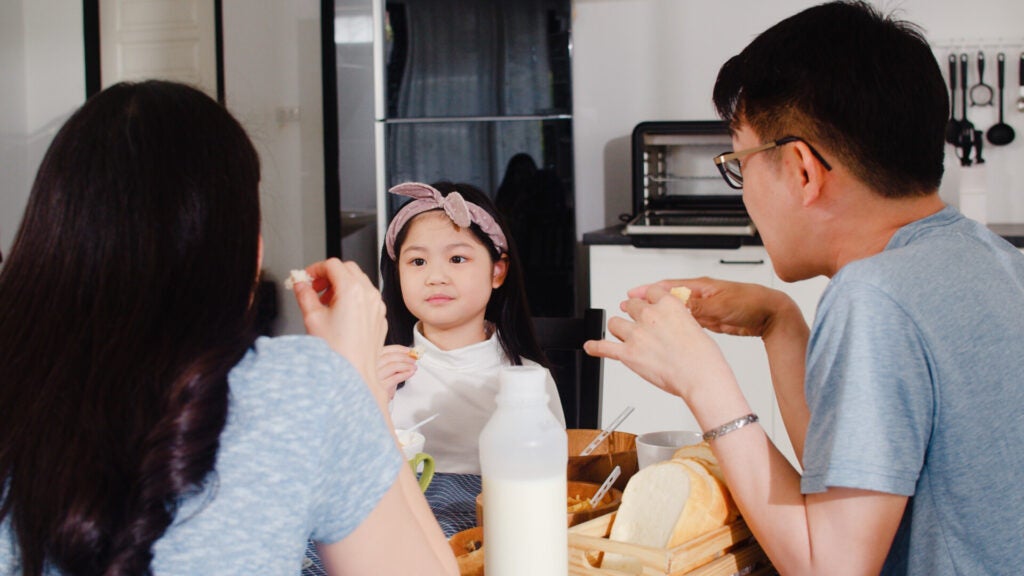 asian japanese family has breakfast home asian mom dad daughter feeling happy talking together while eat bread corn flakes cereal milk bowl table kitchen morning