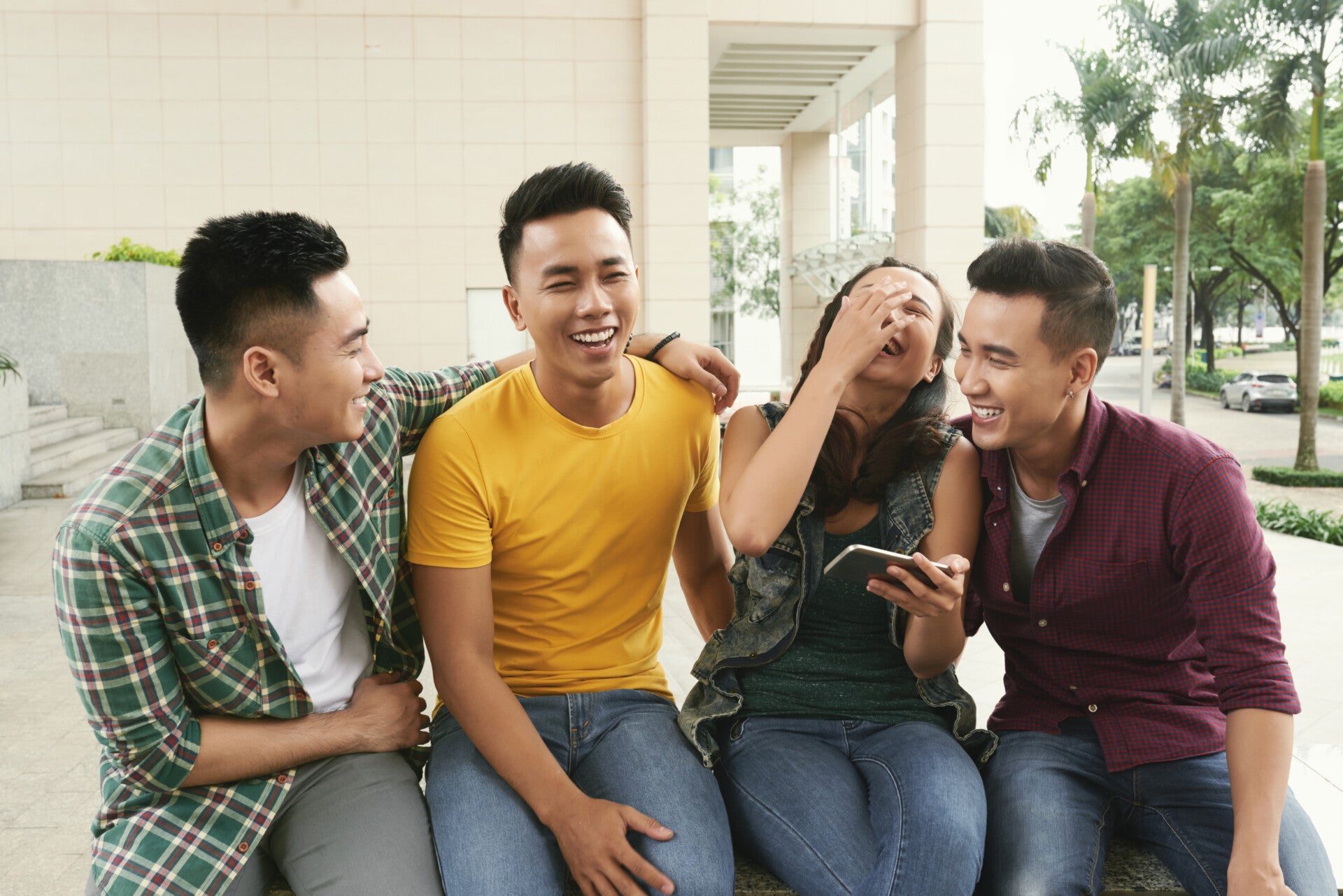 group young asian men girl sitting together urban street laughing