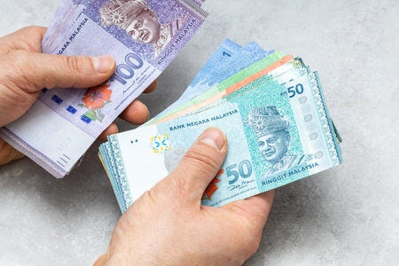 181149679 malaysian money held in both hands lots of ringgit gray background financial business concept