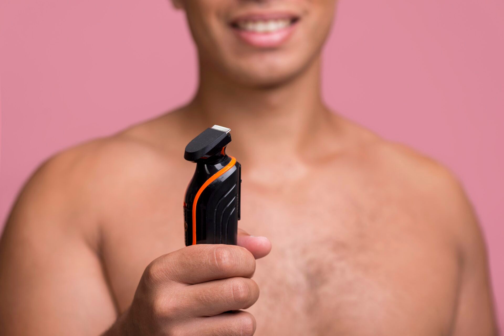 front view defocused smiley man holding electric shaver