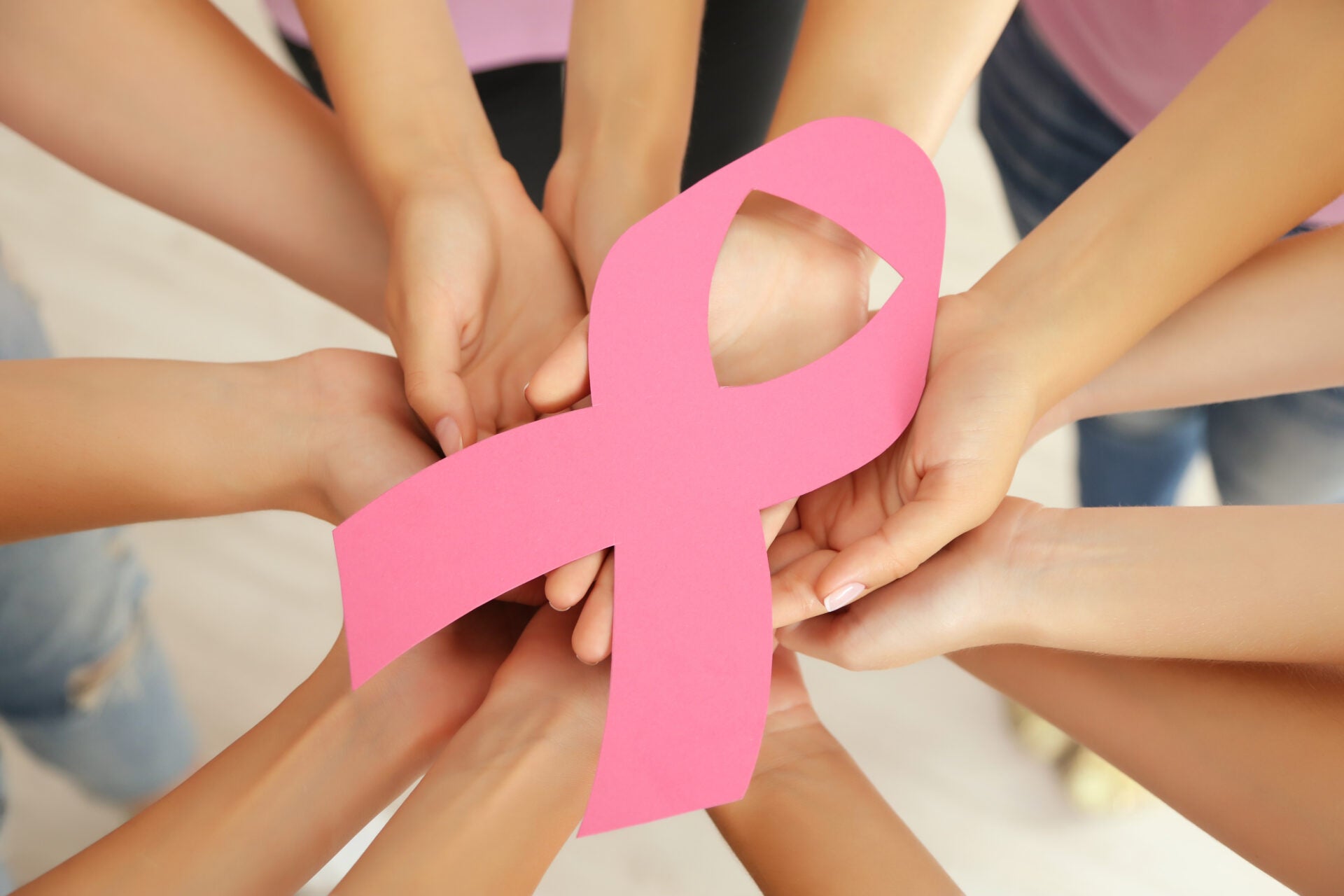 women hands joined circle holding breast cancer symbol