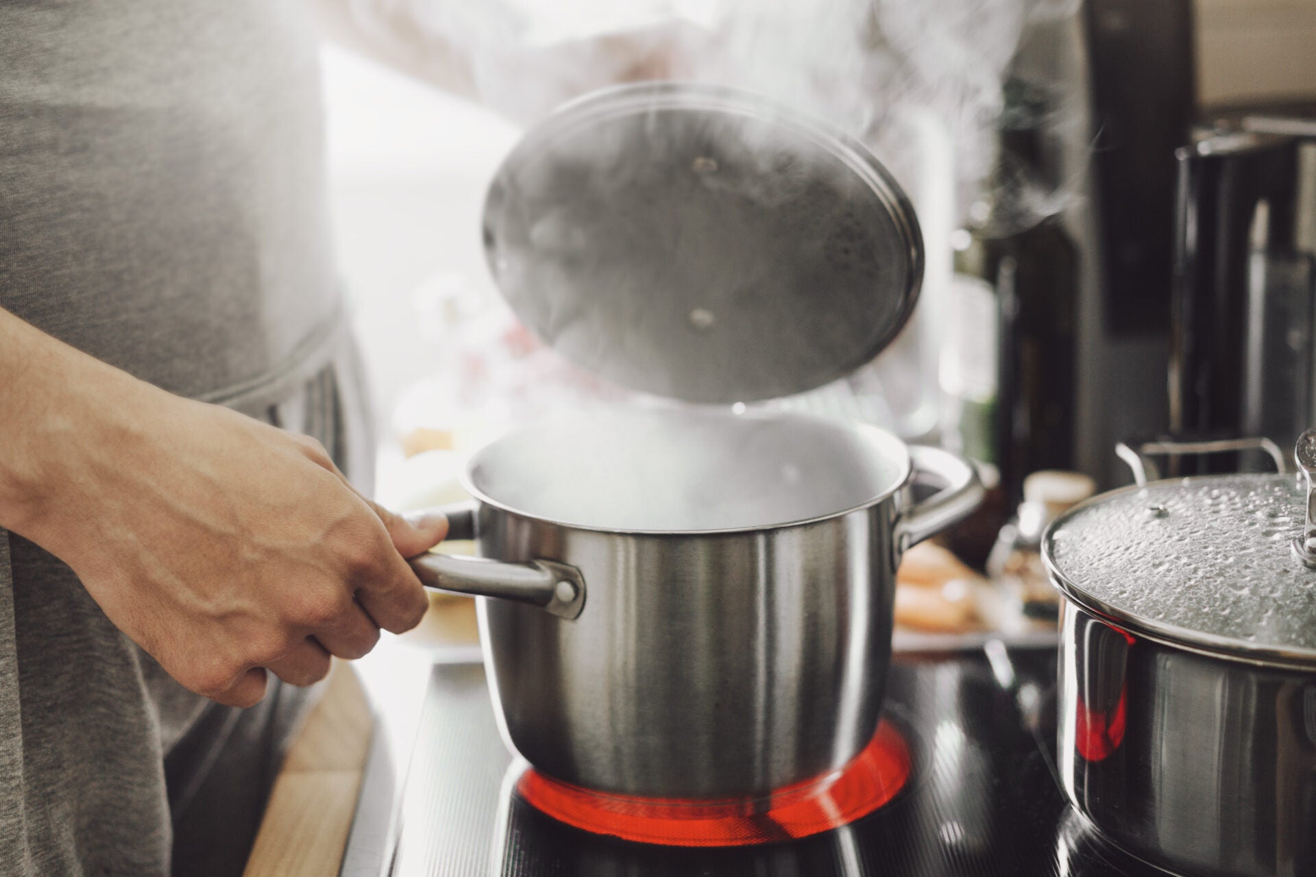 young man cooking fresh food home opening lid steaming pot