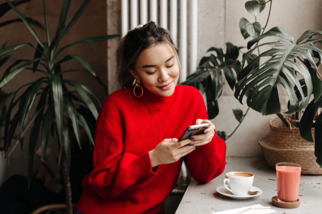 Charming Young Woman Massive Earrings Bright Sweater Chats Phone While Sitting Cafe Cup Coffee
